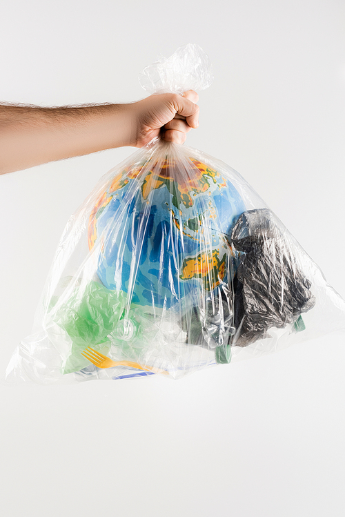 partial view of man holding plastic bag with garbage and globe isolated on grey, ecology concept