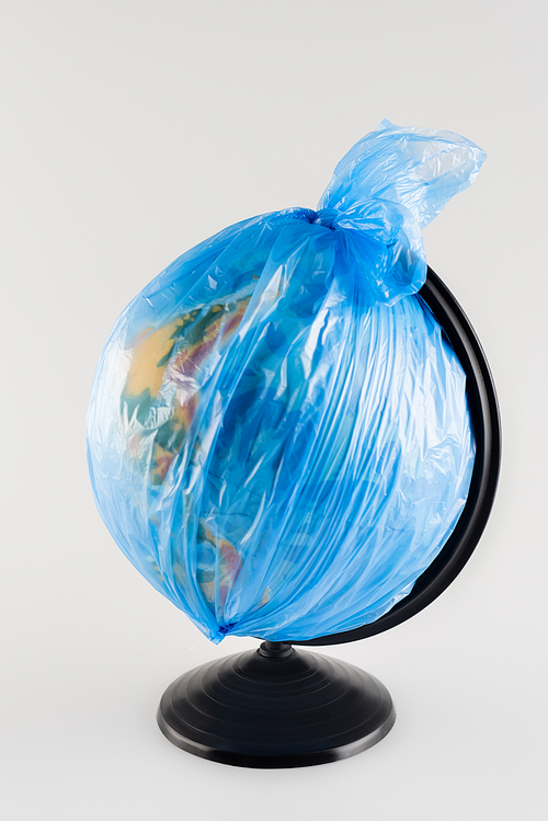 globe packed in plastic bag isolated on grey, ecology concept