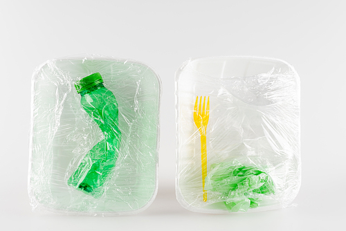 top view of plastic plates with bottle and fork packed in polyethylene, ecology concept