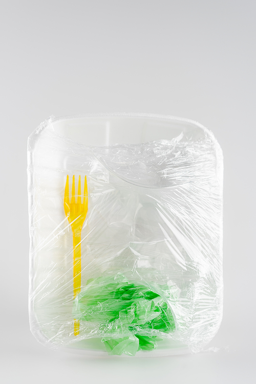 top view of plastic plate, fork and bag packed in cellophane, ecology concept