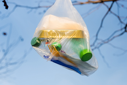 polyethylene bag with can and plastic bottles against blue sky, ecology concept