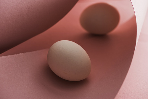 selective focus of chicken eggs in shadow in spiral paper pink swirls