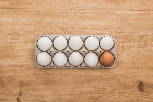 top view of chicken eggs in cardboard box on wooden table