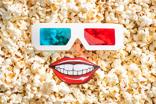top view of 3d glasses and paper cut smiling mouth on crispy popcorn, cinema concept