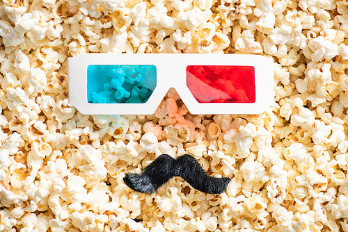 top view of 3d glasses and artificial mustache on scattered popcorn, cinema concept