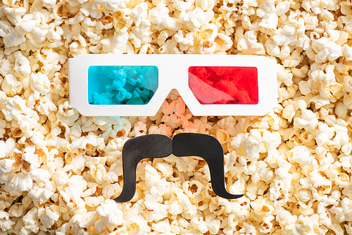 top view of 3d glasses and paper cut mustache on scattered tasty popcorn, cinema concept
