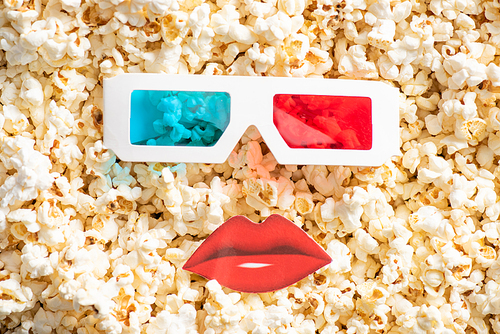 top view of 3d glasses near paper cut lips on tasty popcorn, cinema concept