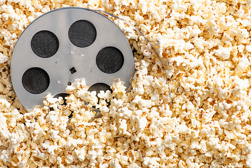 top view of film reel on delicious popcorn, cinema concept