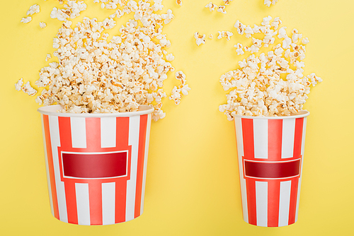 top view of big and small buckets with tasty popcorn on yellow, cinema concept