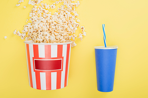bucket of popcorn near cup of soda on yellow, cinema concept