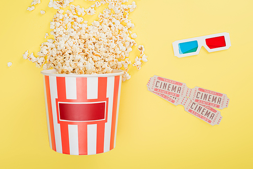 top view of bucket with popcorn, 3d glasses and cinema tickets on yellow