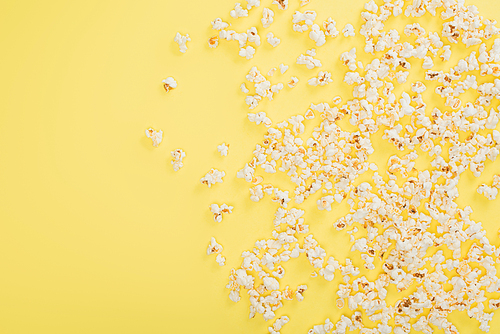 top view of crunchy popcorn scattered on yellow, cinema concept