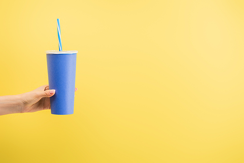 cropped view of woman holding paper cup of soda isolated on yellow, cinema concept