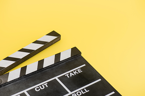 close up view of clapperboard on yellow background, cinema concept