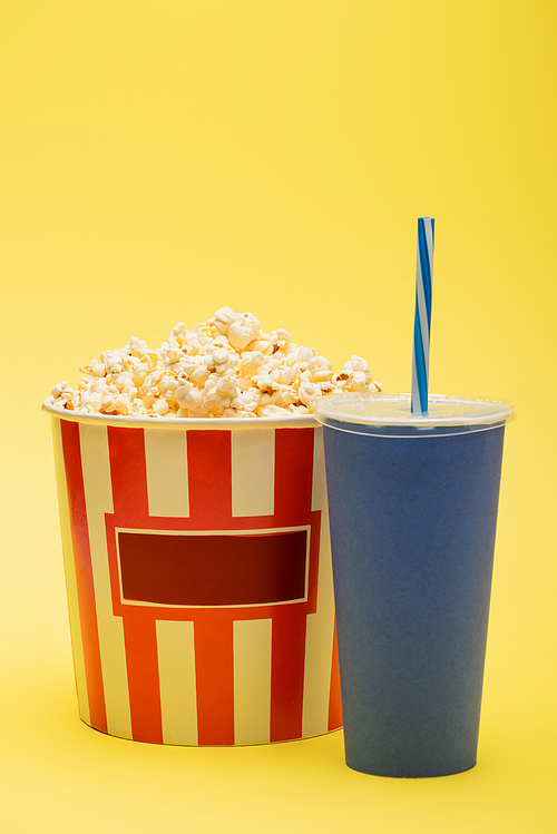 cup of soda near bucket full of tasty popcorn on yellow, cinema concept