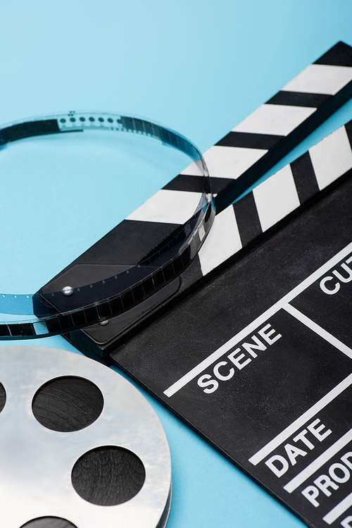 close up view of film reel and clapperboard on blue, cinema concept