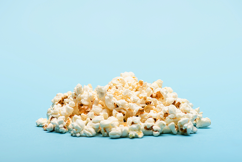 pile of crunchy airy popcorn on blue with copy space, cinema concept