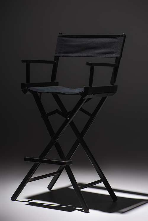modern, black filmmaker chair on dark grey background, cinema concept