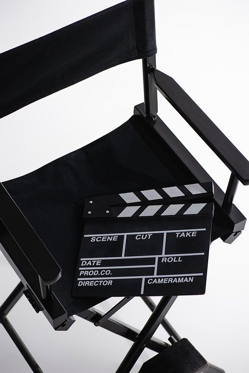 high angle view of clapperboard on director chair on white, cinema concept