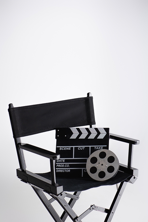 clapperboard and film reel on director chair on white with copy space, cinema concept