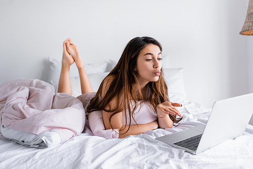 Woman  at laptop on blurred foreground on bed