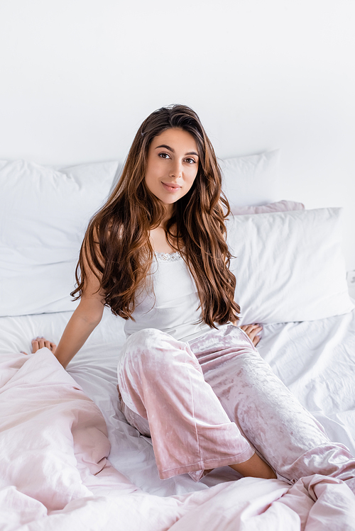 Young woman in pajama sitting on bed at home