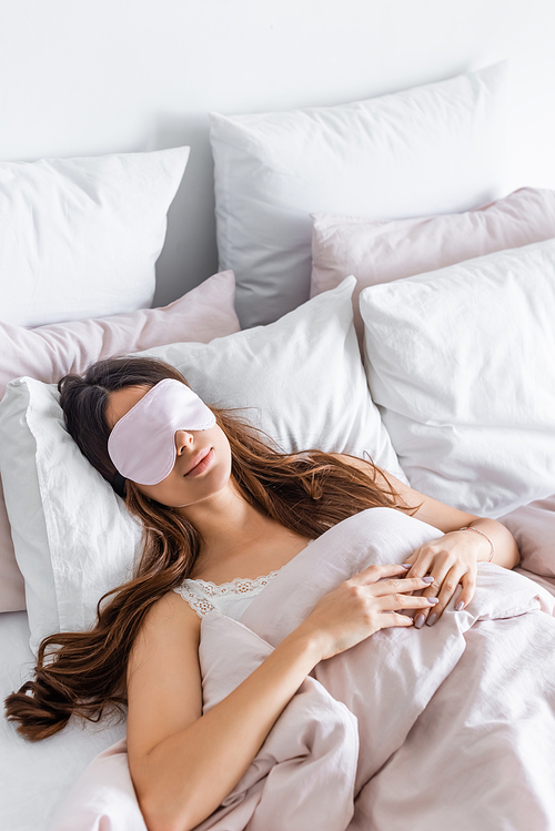 Young woman sleeping in blindfold on while bedding