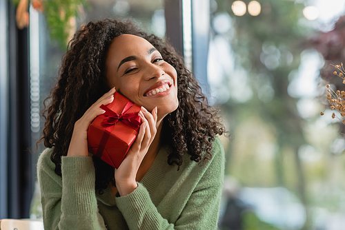 smiling african american woman holding wrapped christmas gift