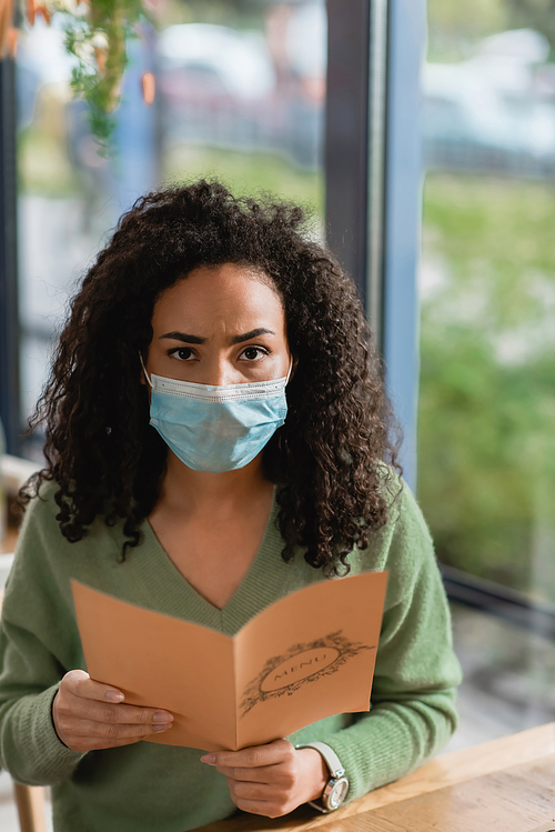 african american woman in medical mask holding menu and 