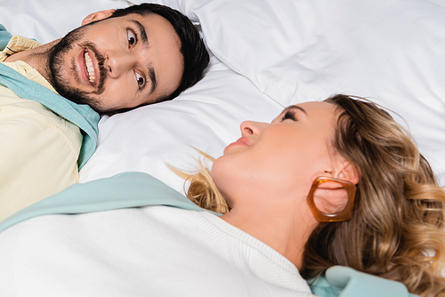 Muslim man smiling at girlfriend on blurred foreground on hotel bed