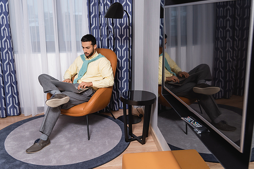 Muslim freelancer using laptop in modern hotel room