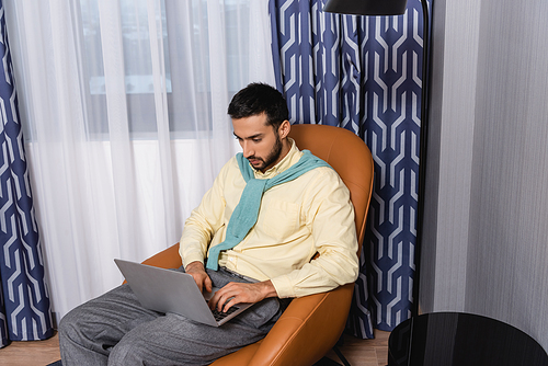 Young muslim freelancer using laptop in hotel room