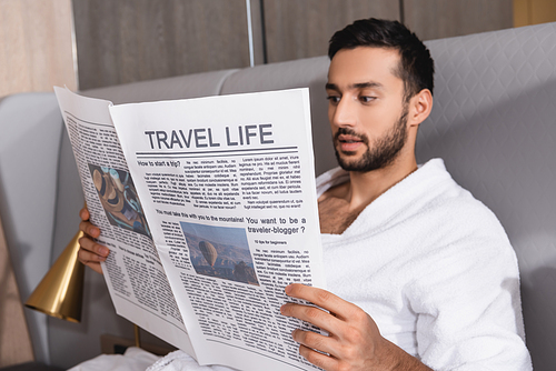 Travel life lettering on newspaper in hands of arabian man in bathrobe in hotel