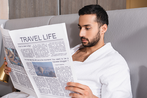Arabian man reading newspaper with travel life on blurred foreground in hotel