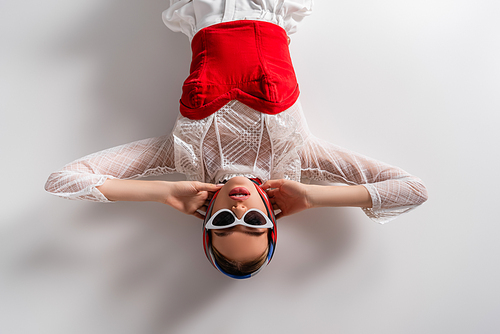 top view of trendy woman in headscarf and sunglasses lying while  on white