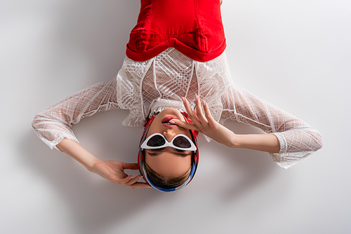 top view of stylish woman in headscarf and sunglasses lying while  on white