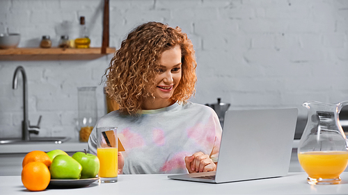 happy young woman holding credit card while shopping online in kitchen