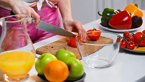Cropped view of woman cutting tomato on chopping board
