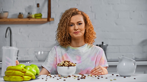 happy and curly woman  near breakfast on kitchen table