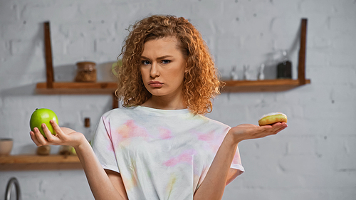 curly young woman choosing between apple  and donut