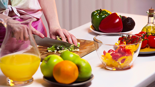 cropped view of woman cutting lettuce on chopping board