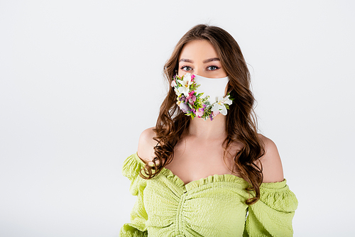 Brunette woman in medical mask with flowers and green blouse  isolated on grey