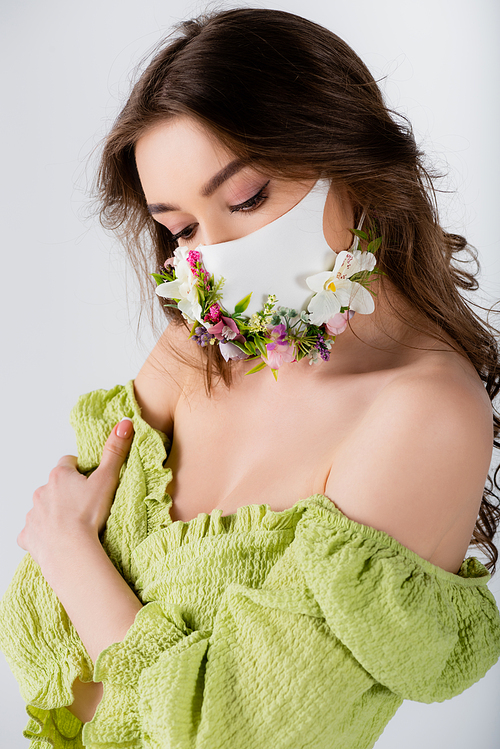 Woman in stylish blouse and medical mask with flowers isolated on grey
