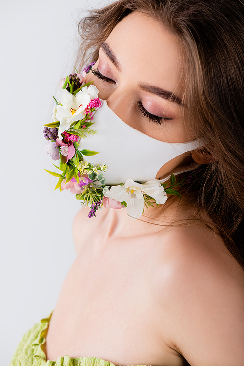 Model with closed eyes and white medical mask with flowers isolated on grey