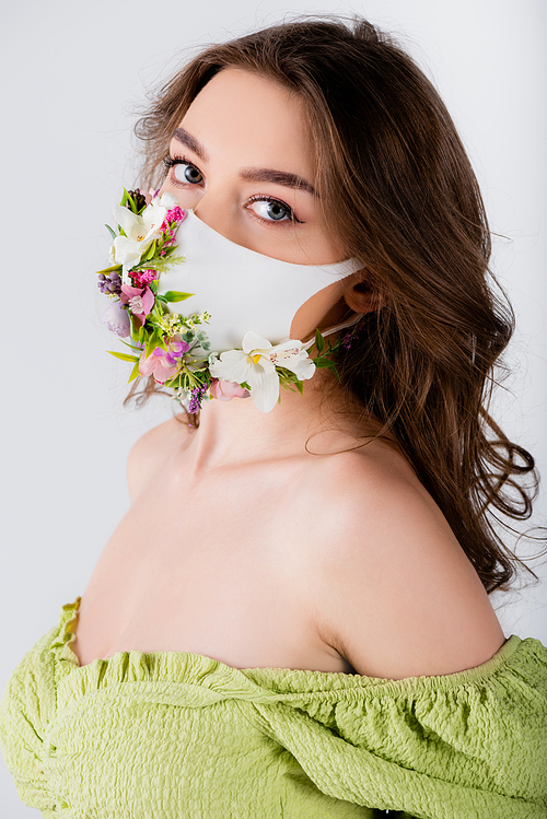 Brunette woman in trendy blouse and medical mask with flowers  isolated on grey