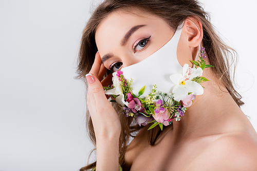 Woman in medical mask with flowers and hand near forehead  isolated on grey