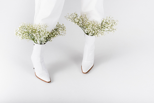 Cropped view of woman in white shoes with flowers on grey background