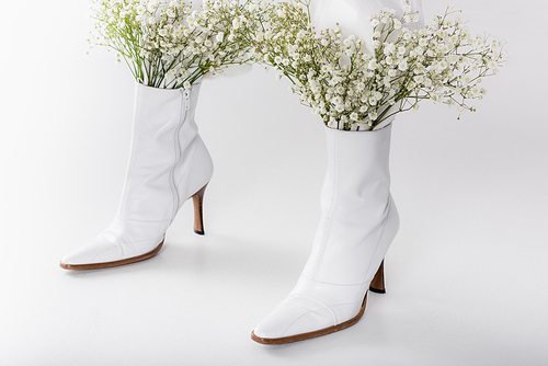 Cropped view of legs of woman in white shoes with small flowers on grey background