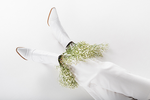 High angle view of white baby breath flowers in shoes of woman on grey background
