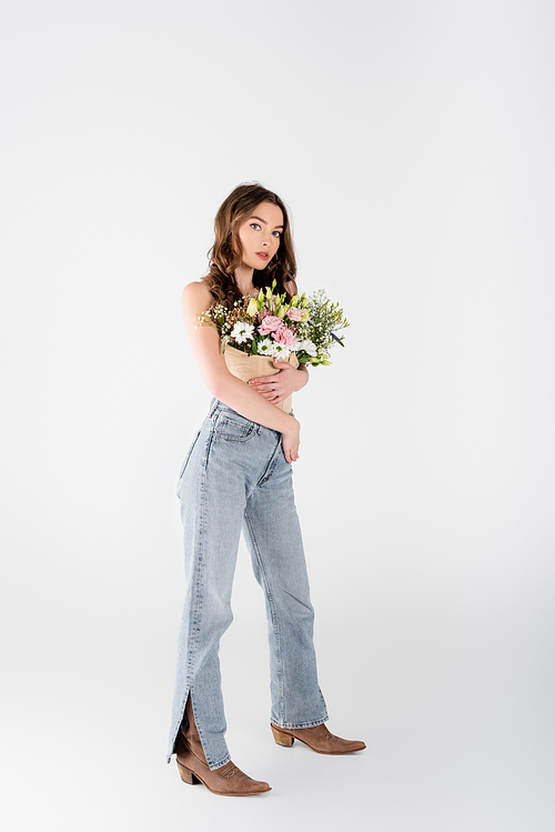 Full length of stylish model with flowers in blouse  on grey background